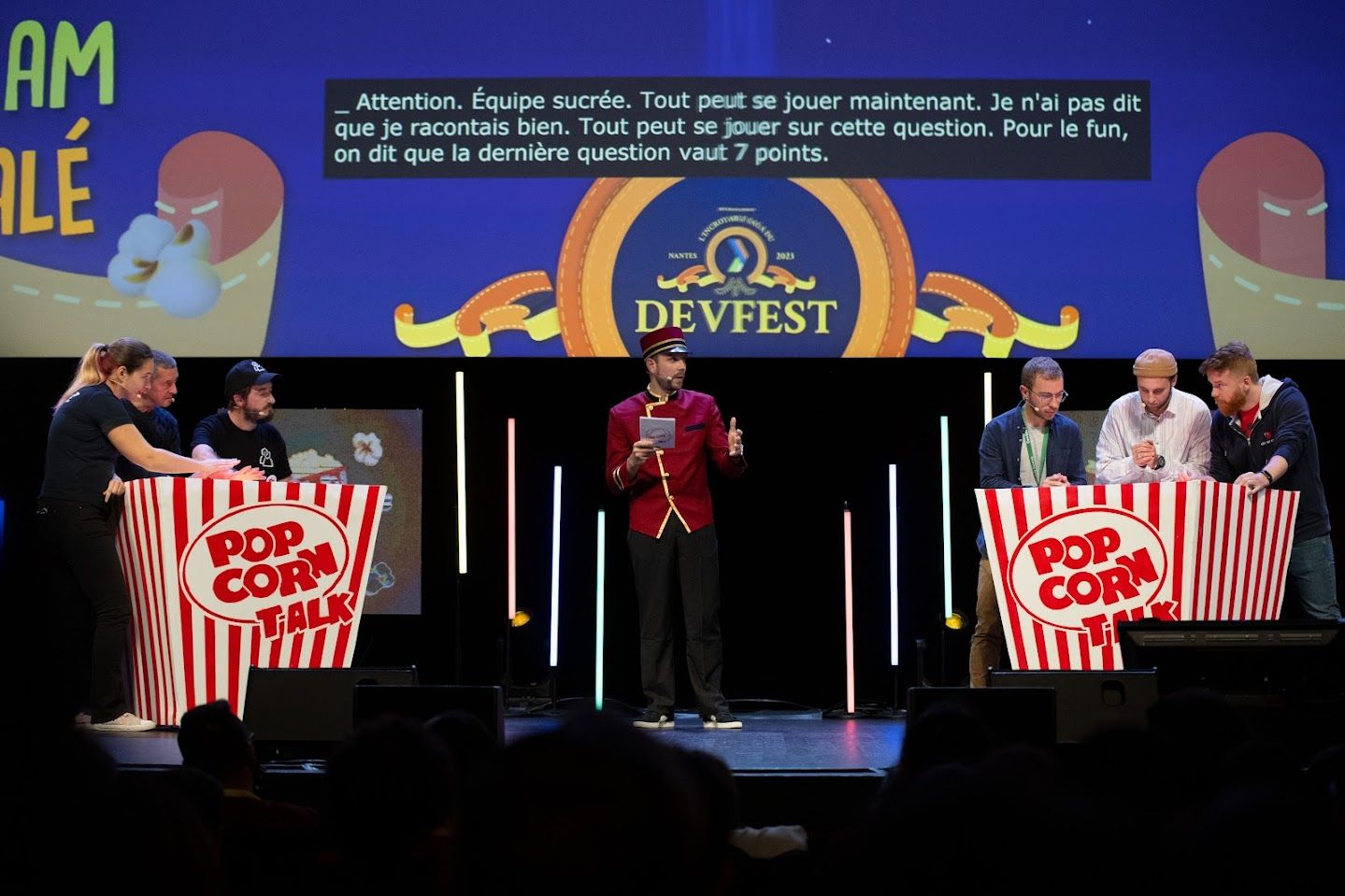 Photo de la keynote de cloture popcorn talk (2 énorme pots de pop-corn avec 3 personnes et au milieu, un présentateur)
